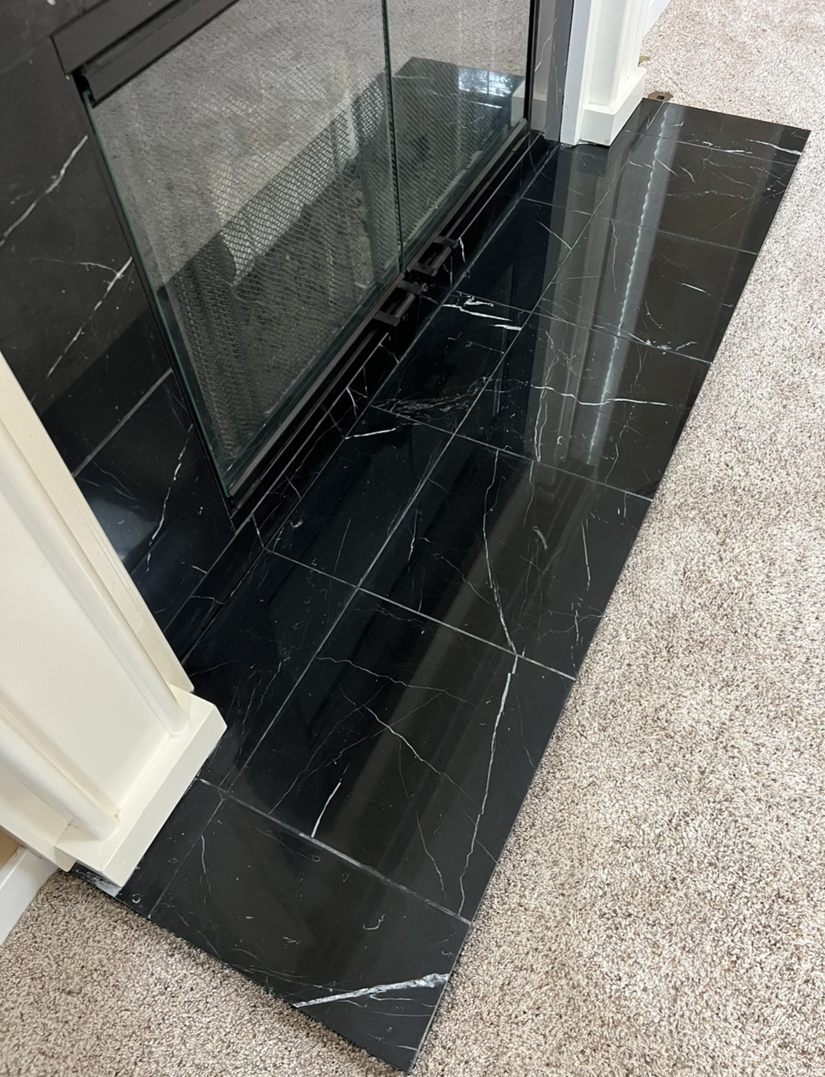 Restored high-gloss black marble fireplace surround after professional refinishing