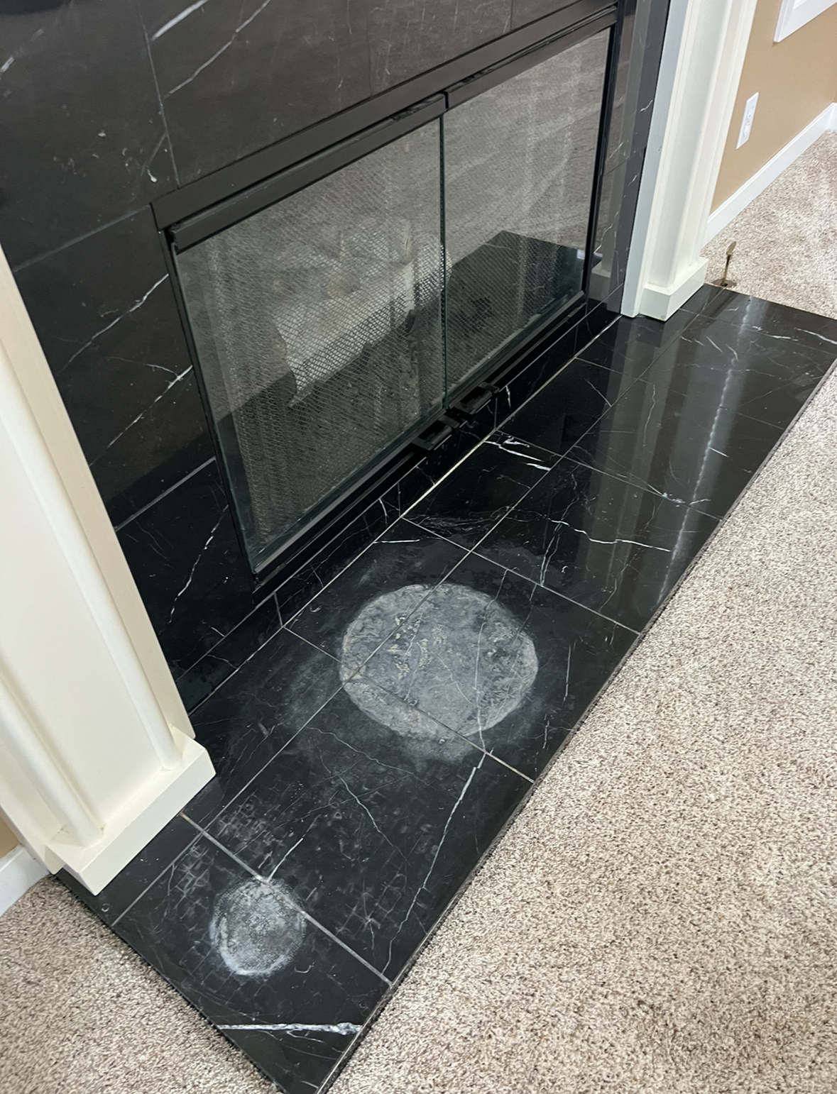 Etched and dull black marble fireplace surround before refinishing